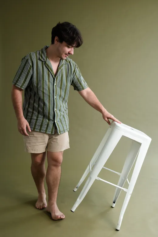 Leonel ao lado de um banquinho, em estúdio