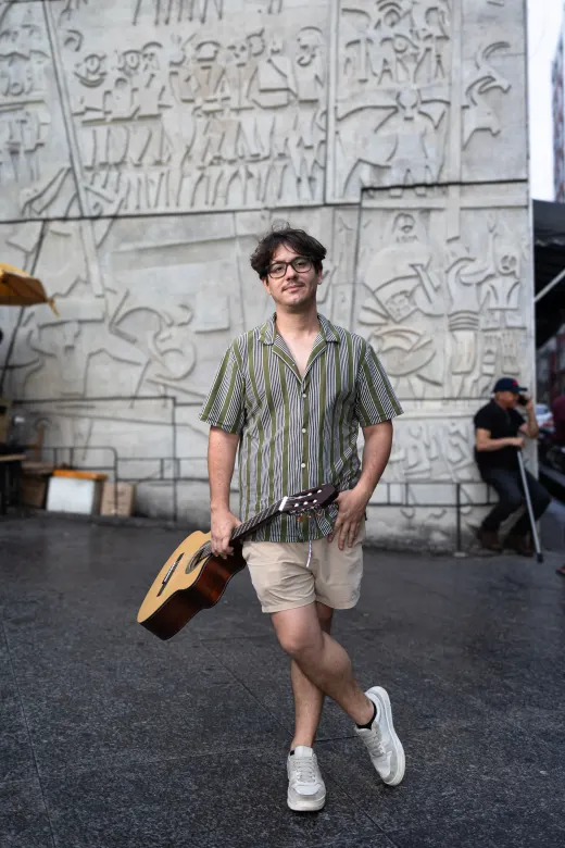Leonel caminhando com o violão pela cidade